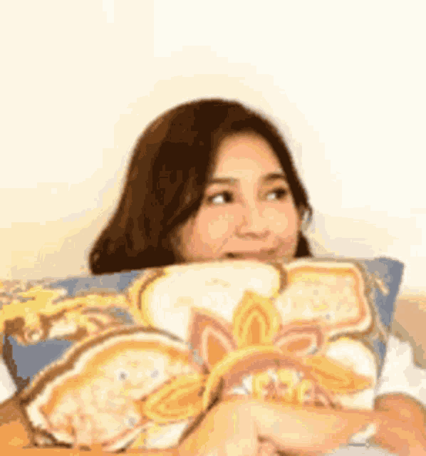 a woman is laying on a bed with a pillow on her face .