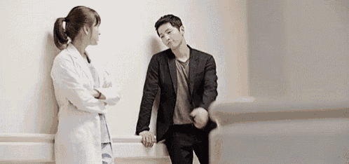 a man in a suit and a woman in a lab coat are standing next to each other .