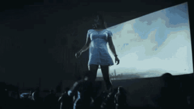 a woman in a white dress is standing on a stage in front of a crowd .