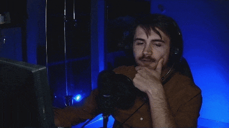 a man sitting in front of a microphone with his hands on his head