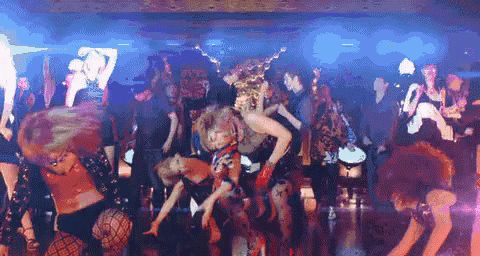 a crowd of people are dancing in a dark room with blue lights