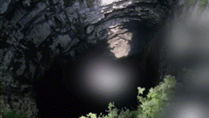 a dark cave with a light coming out of the top