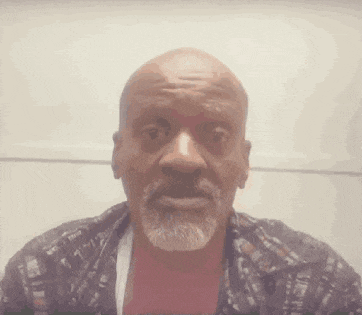 a bald man with a beard is wearing a plaid shirt and making a surprised face .