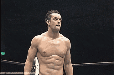 a shirtless wrestler is standing in a wrestling ring with his hands on his hips .