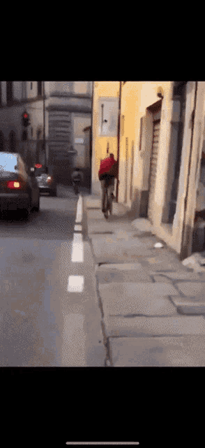 a man is riding a bike down a narrow street