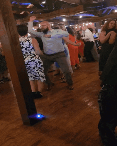 a group of people are dancing in a room with a blue light in the middle