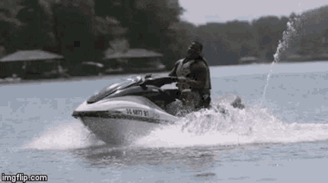 a man is riding a jet ski on a lake while spraying water .