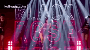 a woman is dancing on a stage in front of the word black rose .