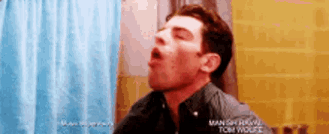 a man is taking a shower with a blue shower curtain behind him