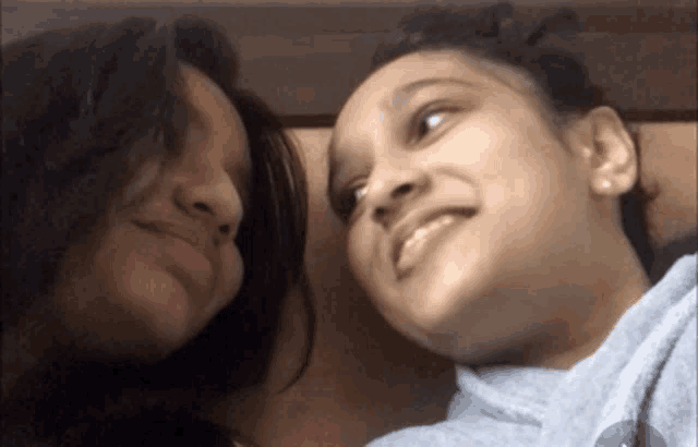 two girls are looking at each other and smiling at the camera