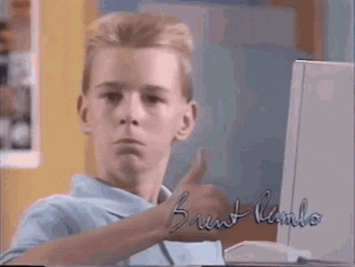 a young boy is giving a thumbs up in front of a computer with the name brent kamlo on it