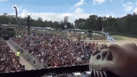 a large crowd of people are gathered at a concert with a t-rex head in the foreground