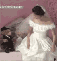 a woman in a wedding dress is standing in front of a teddy bear .