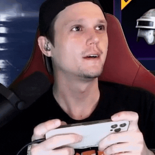a man in a baseball cap is holding a cell phone in his hands .
