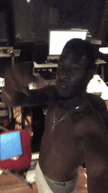 a man without a shirt is standing in front of a monitor