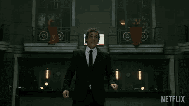 a man in a suit and tie is standing in front of a screen that says netflix