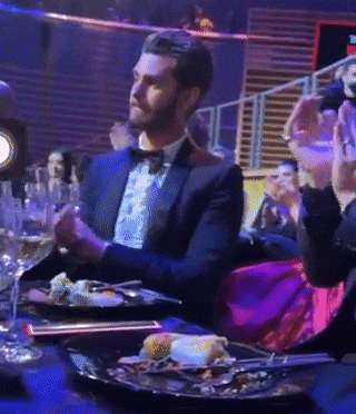 a man in a tuxedo is sitting at a table with plates of food on it