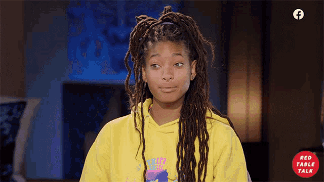 a girl with dreadlocks is wearing a yellow hoodie that says " red table talk " on it
