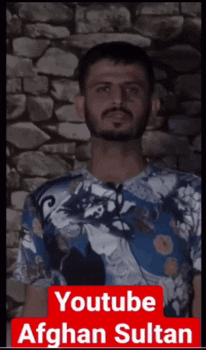 a man with a beard is standing in front of a brick wall and is a youtube afghan sultan