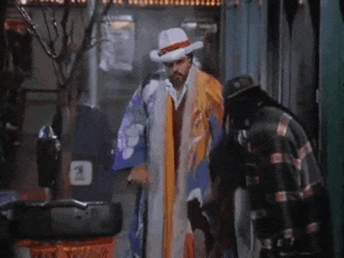 a man in a clown costume is walking down the street with a cane and a hat .