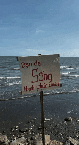 a sign on the beach says ban da song hạnh phúc dua