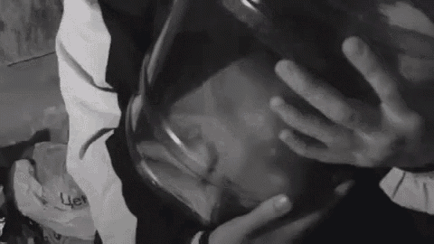 a black and white photo of a person holding a large glass jar .