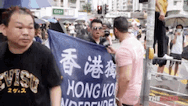 a man is holding a blue flag that says hong kong independent on it .