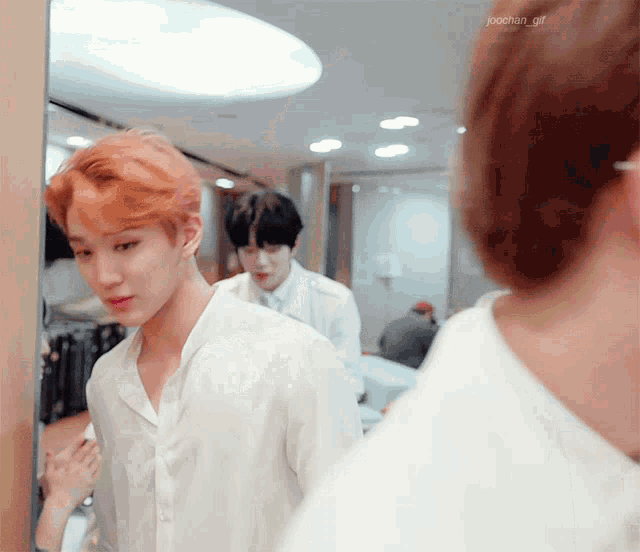 a man with orange hair is looking at himself in the mirror