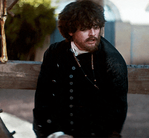 a man with curly hair and a beard wearing a black jacket