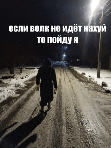 a person walking down a snowy road at night with russian writing