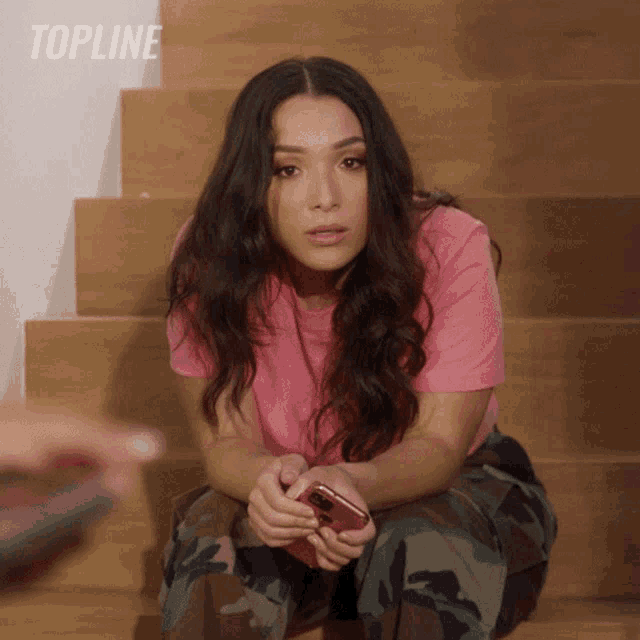 a woman in a pink shirt sits on a set of wooden stairs with the word topline on the bottom