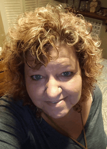 a woman with curly red hair and blue eyes smiles for the camera