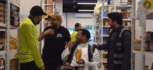 a group of men are standing in a store with one wearing a shirt that says ' nano bag ' on it