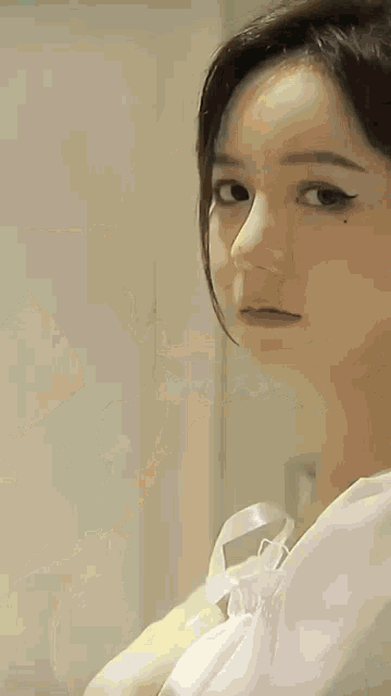 a close up of a woman 's face with a white dress on .