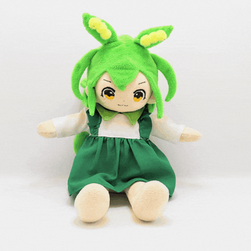 a stuffed doll with green hair and yellow eyes is wearing a green dress