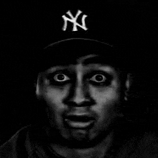 a black and white photo of a man wearing a new york yankees baseball cap .