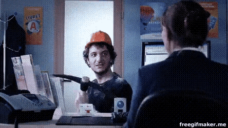 a man wearing an orange hard hat is talking to a woman in front of a poster that says livret a