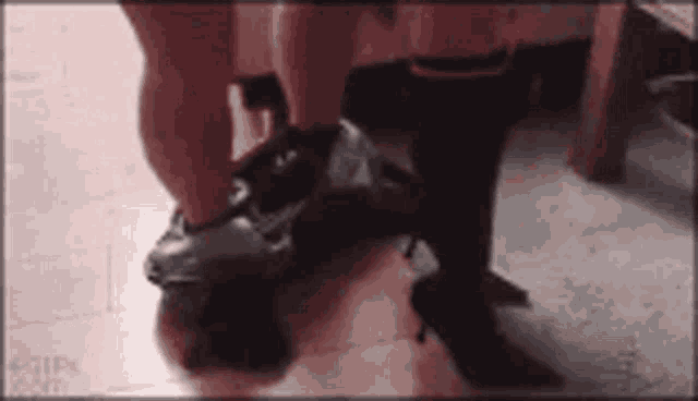 a person wearing high heels is standing on a floor .