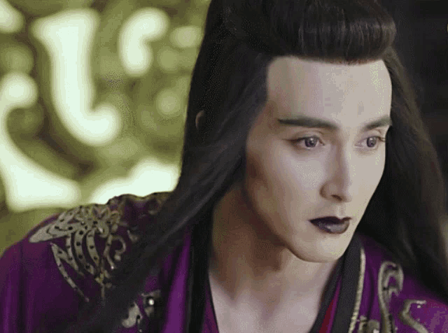 a man with long hair and black lipstick is wearing a purple robe