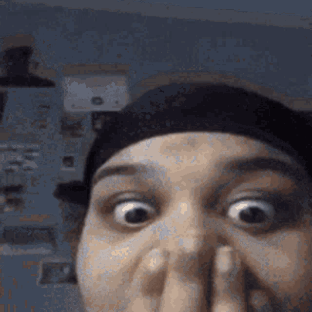 a close up of a person covering their nose with their hand and making a funny face .