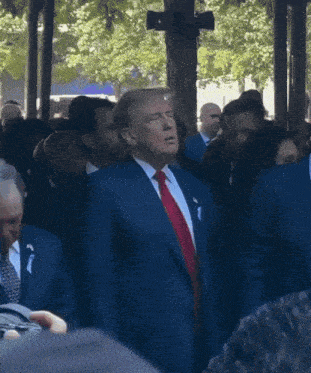 a man in a suit and tie stands in a crowd of people