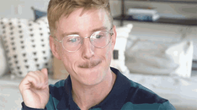 a man wearing glasses and a striped shirt is making a face