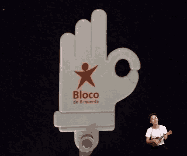 a man playing a guitar in front of a sign that says bloco de esquerda