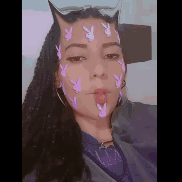 a woman with purple playboy bunnies on her face makes a funny face