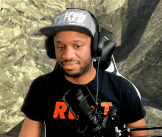 a man wearing headphones and a baseball cap is sitting in front of a microphone .