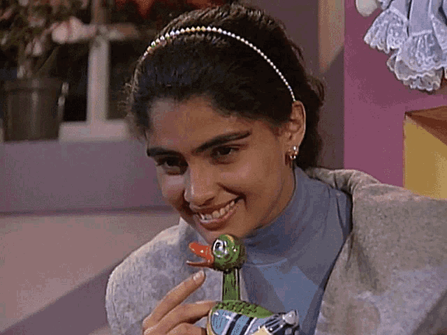 a woman is smiling while holding a green duck toy