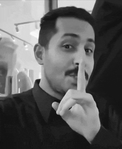 a man with a mustache is making a silence gesture