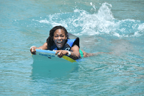 a woman is smiling while riding a boogie board in the ocean