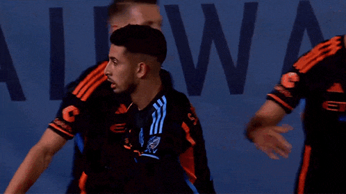 a soccer player wearing a black and orange adidas shirt