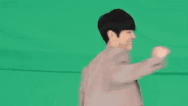 a man in a suit and a white shirt is dancing on a green screen .